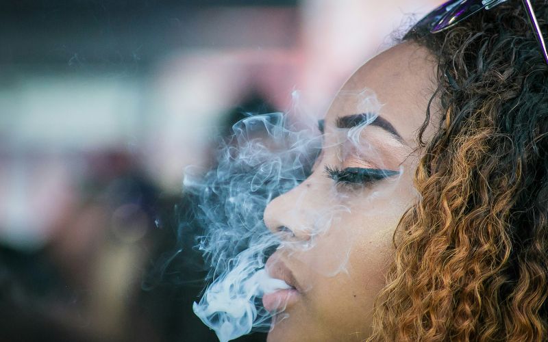 Close up of a woman as she exhales smoke