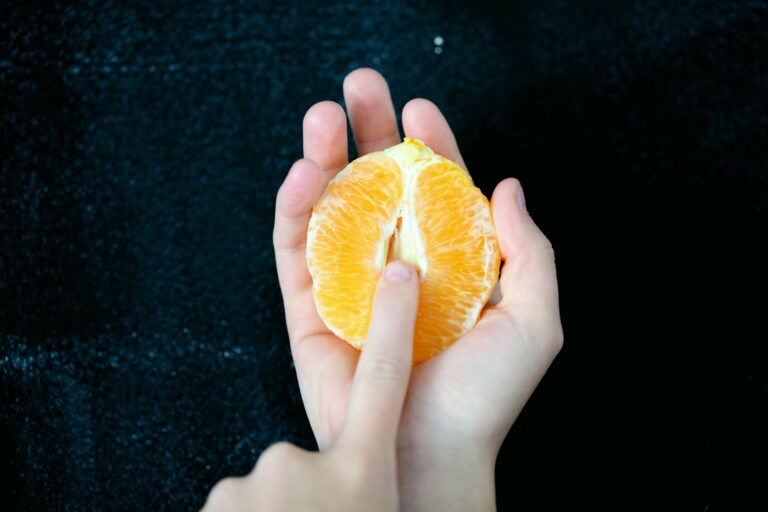 A woman's finger over a half cut orange, simulating masturbation