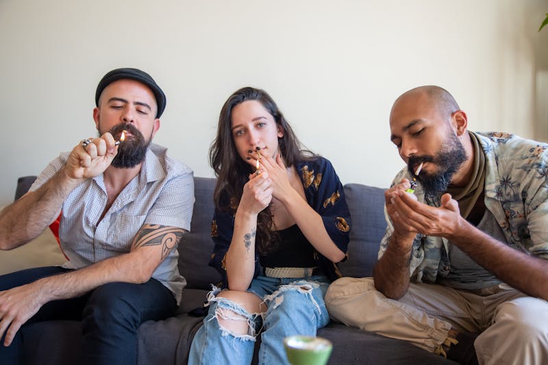 Millennials smoking cannabis pre rolls on a couch