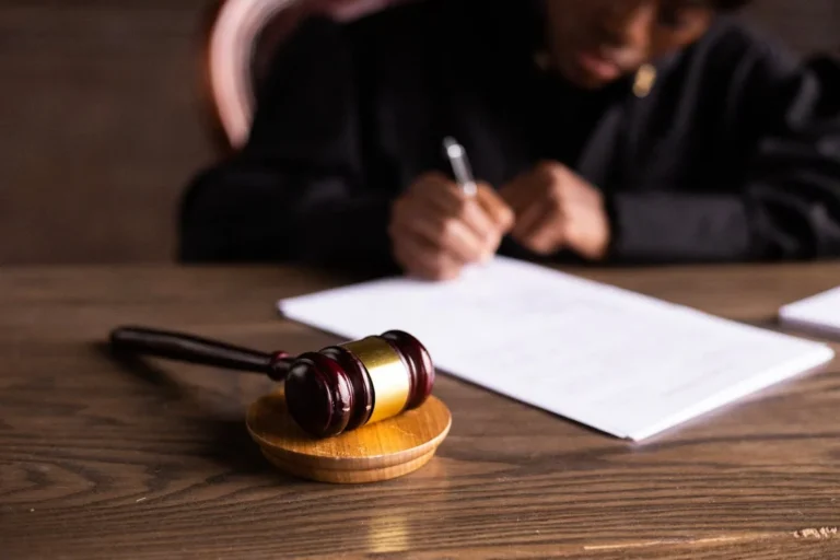 a judge signs papers with a gavel in the forefront